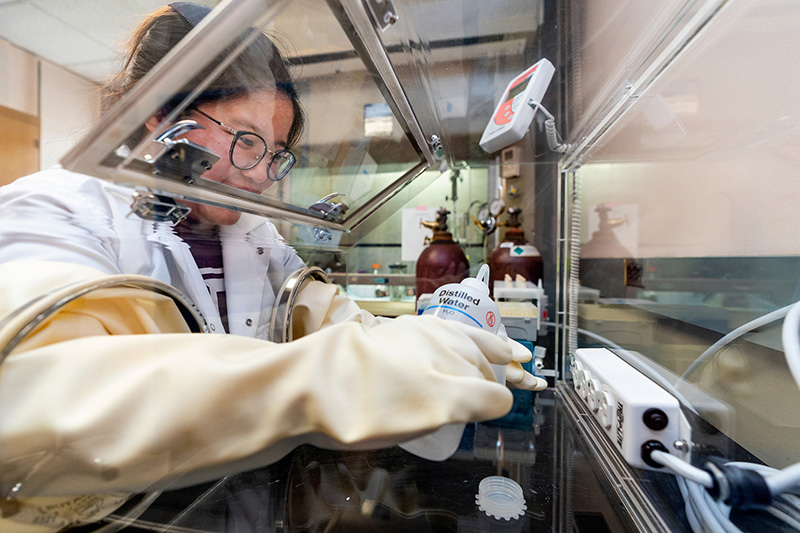 Woman working behind glass in laboratory